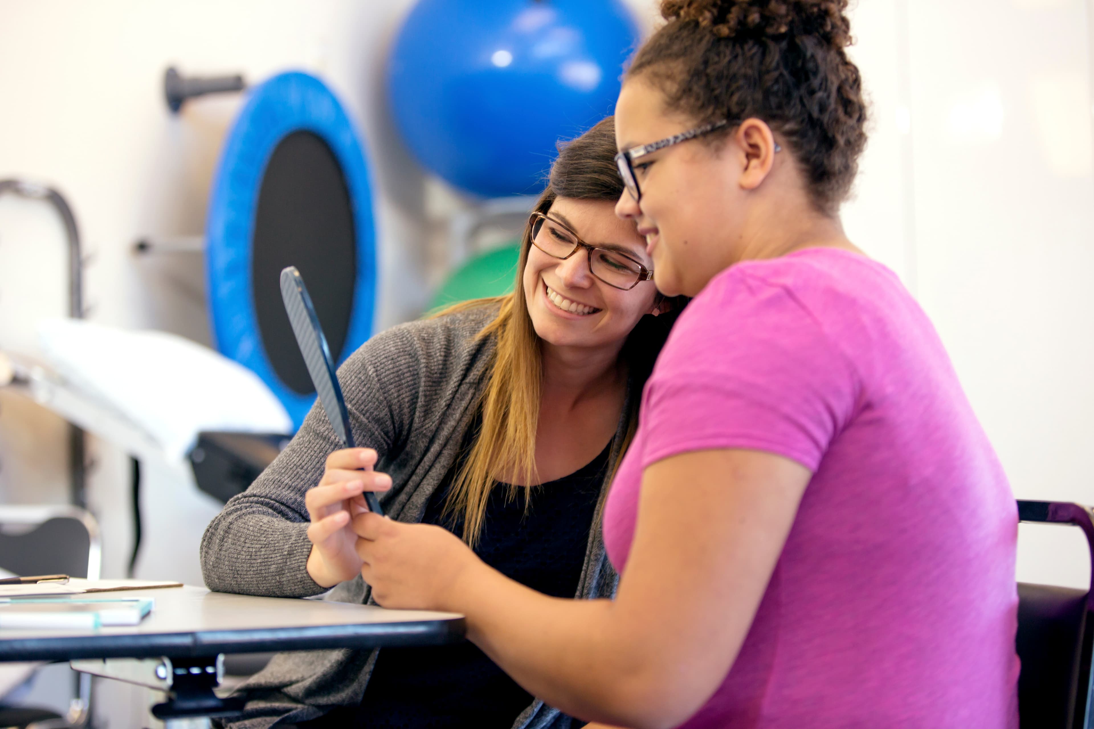 Teenage girl using a mirror for speech therapy with the guidance of a speech therapist
